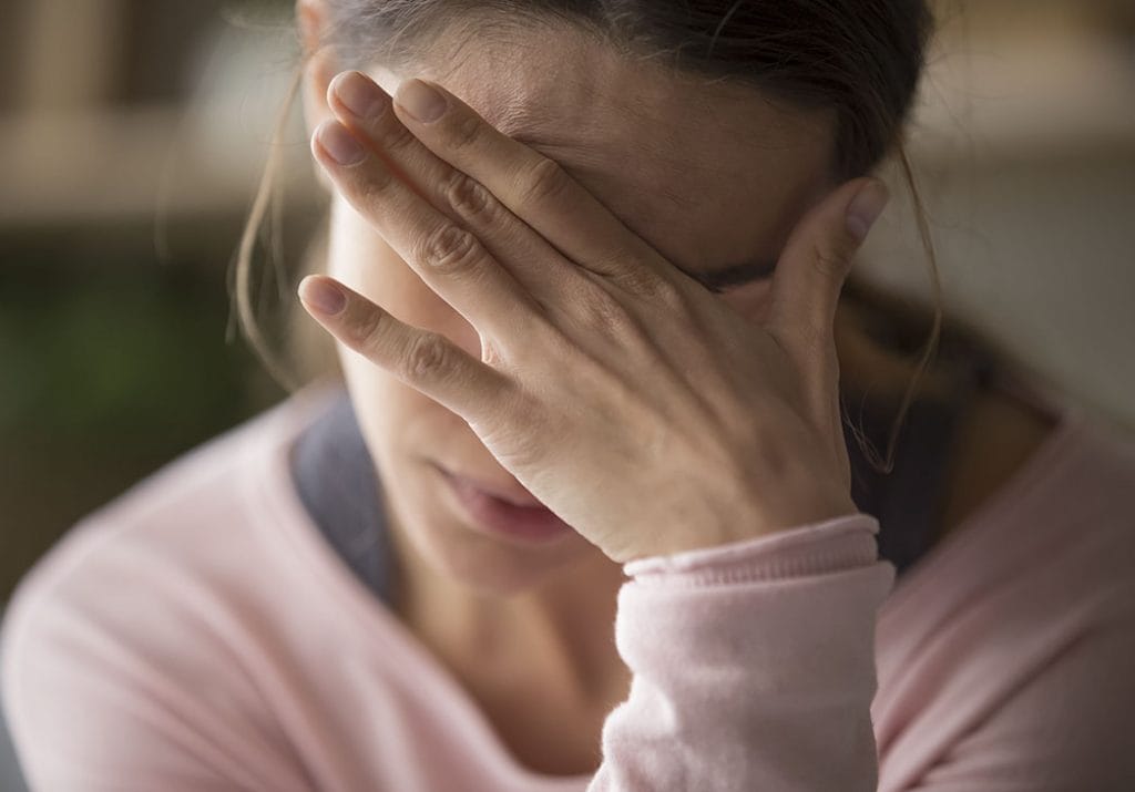 Triste jovem cansada tocando a testa com dor de cabeça enxaqueca ou depressão, chateada garota frustrada incomodada com o problema se sente estressada capa chorando rosto com a mão sofre de conceito de tristeza e tristeza