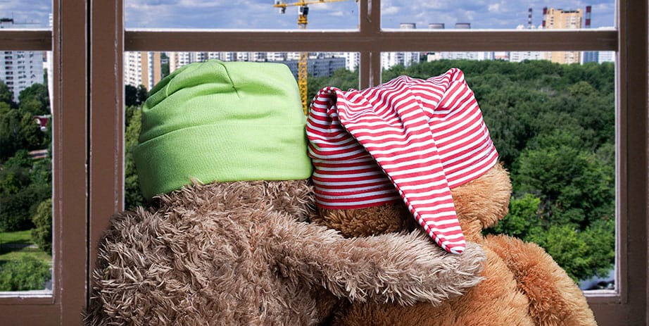 Dois amigos olhando pela janela. Panorama da cidade. Construção, guindaste. Brinquedos coloridos chapéus de urso filhotes. Abrace a janela. Conceito - amizade e apoio.