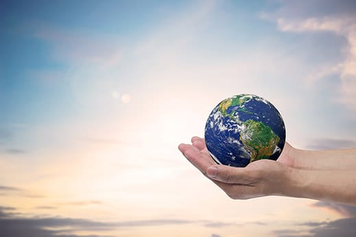 Mão segurando o planeta terra com céu de fundo