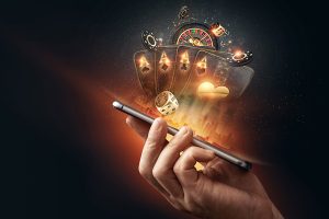 Fundo criativo, cassino online, um homem segura um smartphone com cartas de baralho, roleta e fichas, fundo preto e dourado. Conceito de jogos de azar online. Espaço para texto.