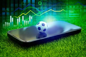 Tela de celular com bola de futebol e gráficos ao fundo