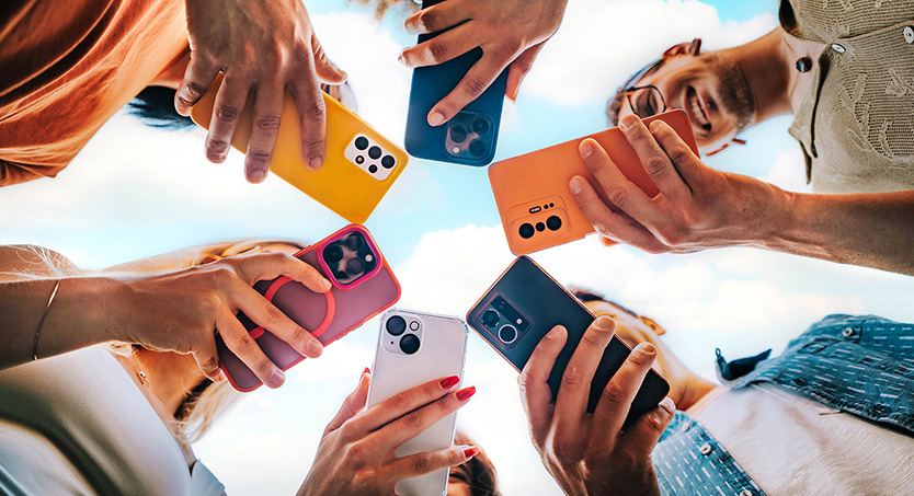 Grupo de jovens usando smartphones ao ar livre - Mulheres e homens da geração Y navegando juntos em seus celulares - Conceito de tecnologia moderna com rapazes e moças usando celulares na rua